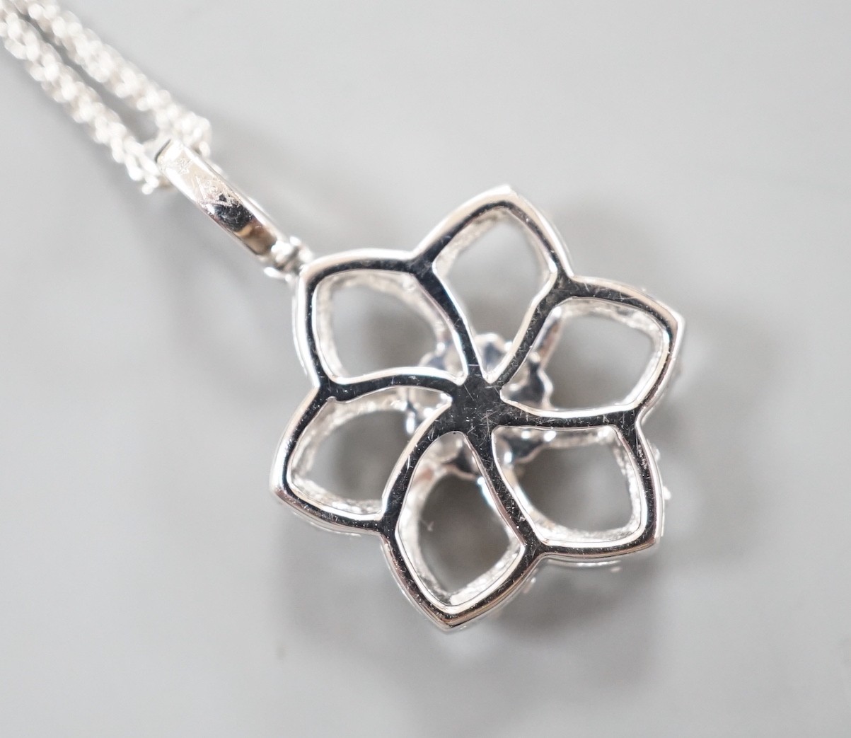 A modern 750 white metal and diamond chip set openwork flower head cluster pendant, overall 24mm, on an 18ct white gold fine link chain, 40cm, gross weight 4.9 grams